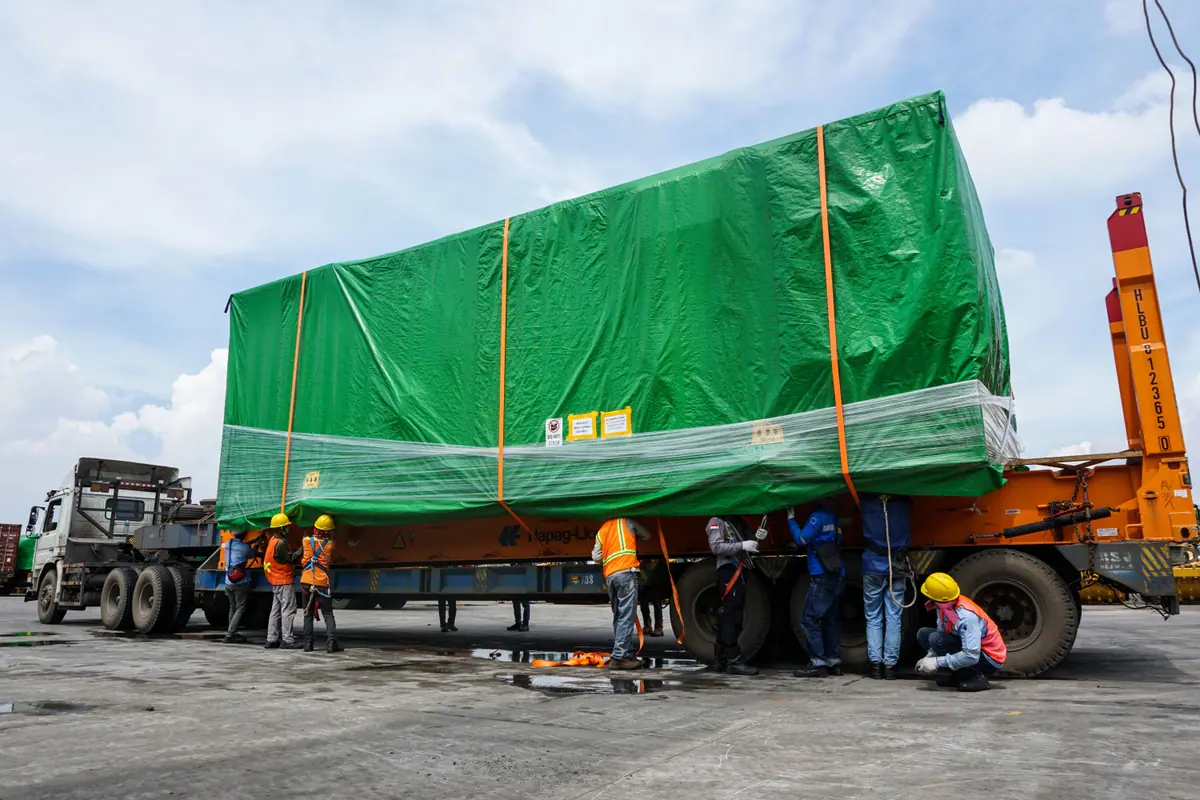 Muatan proyek berukuran besar terbungkus terpal di atas trailer